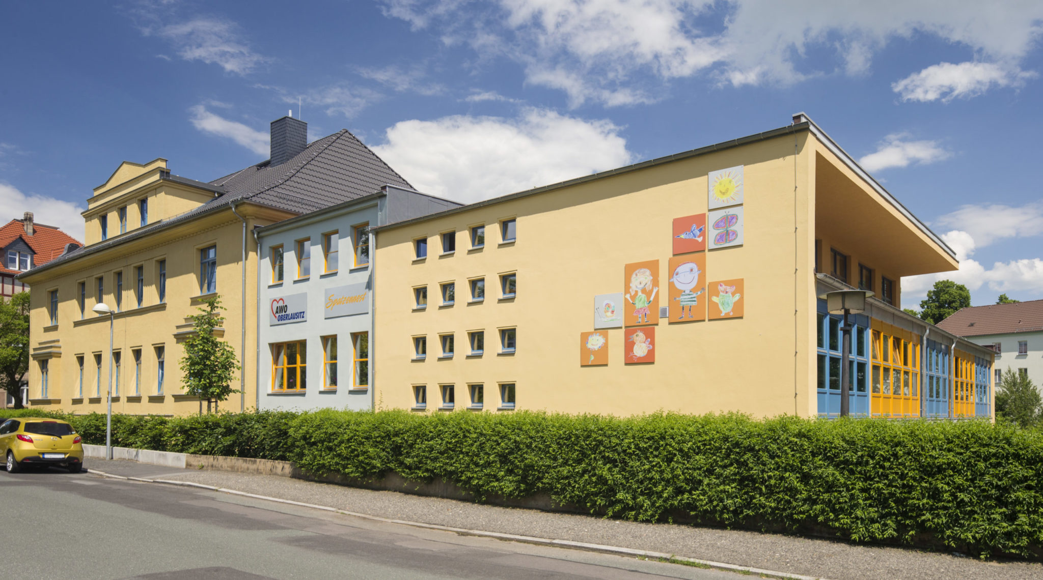 Blick auf die Einrichtung von außen. An der Wand sind verschiedene Kinderzeichnungen