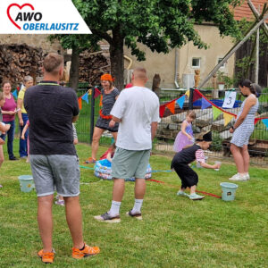 Kinder und Erwachsene spielen auf der Wiese ein Wassertransportspiel