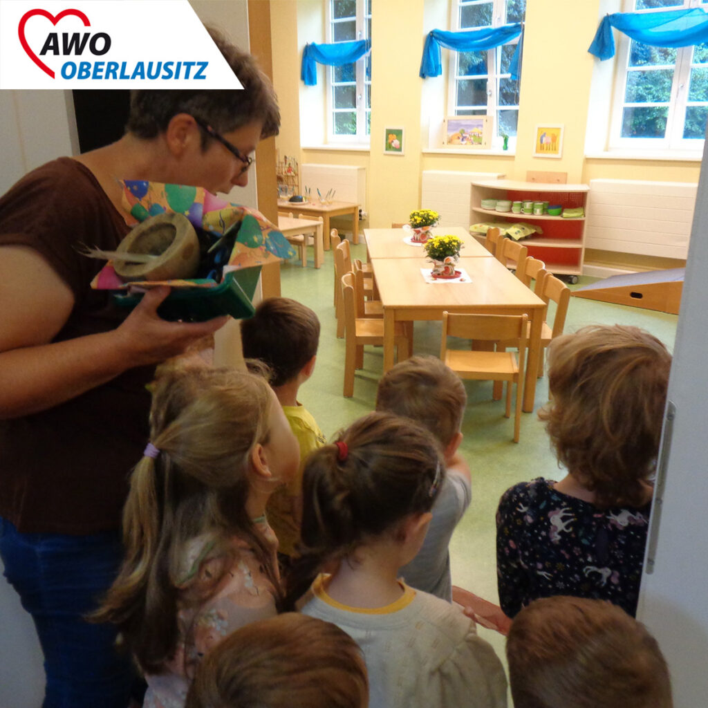 Viele Kinder schauen durch die Tür und entdecken den Raum mit den gedeckten Tischen.