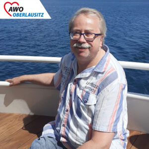 Ein Mann sitzt glücklich auf dem Deck des Bootes.
