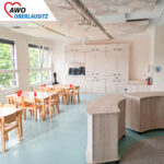 geräumiger Gruppenraum mit Tischen und bewegbaren Schränken