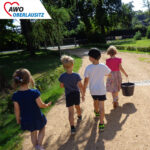 vier Kinder laufen um einen Eimer Äpfel wegzubringen