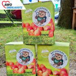 Drei Tetrapacks mit Apfelsaft. Darauf eine Plakette mit dem neuen Naturpark-Kita-Logo.