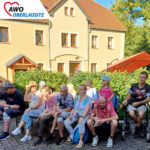 Besucher und Bewohner mit Familien auf dem Gelände des Dreiseithofes in der Sonne
