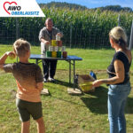 Frau und Junge probieren sich im Dosenwerfen