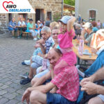 Besucher und Bewohner mit Familien auf dem Gelände des Dreiseithofes in der Sonne