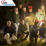 Vor einem weihnachtlichen Holzstern stehen und hocken aufgereiht die engagierten Mitarbeiter des Altenheims.