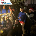 Vor einem weihnachtlichen Holzstern stehen und hocken aufgereiht die engagierten Mitarbeiter des Altenheims.