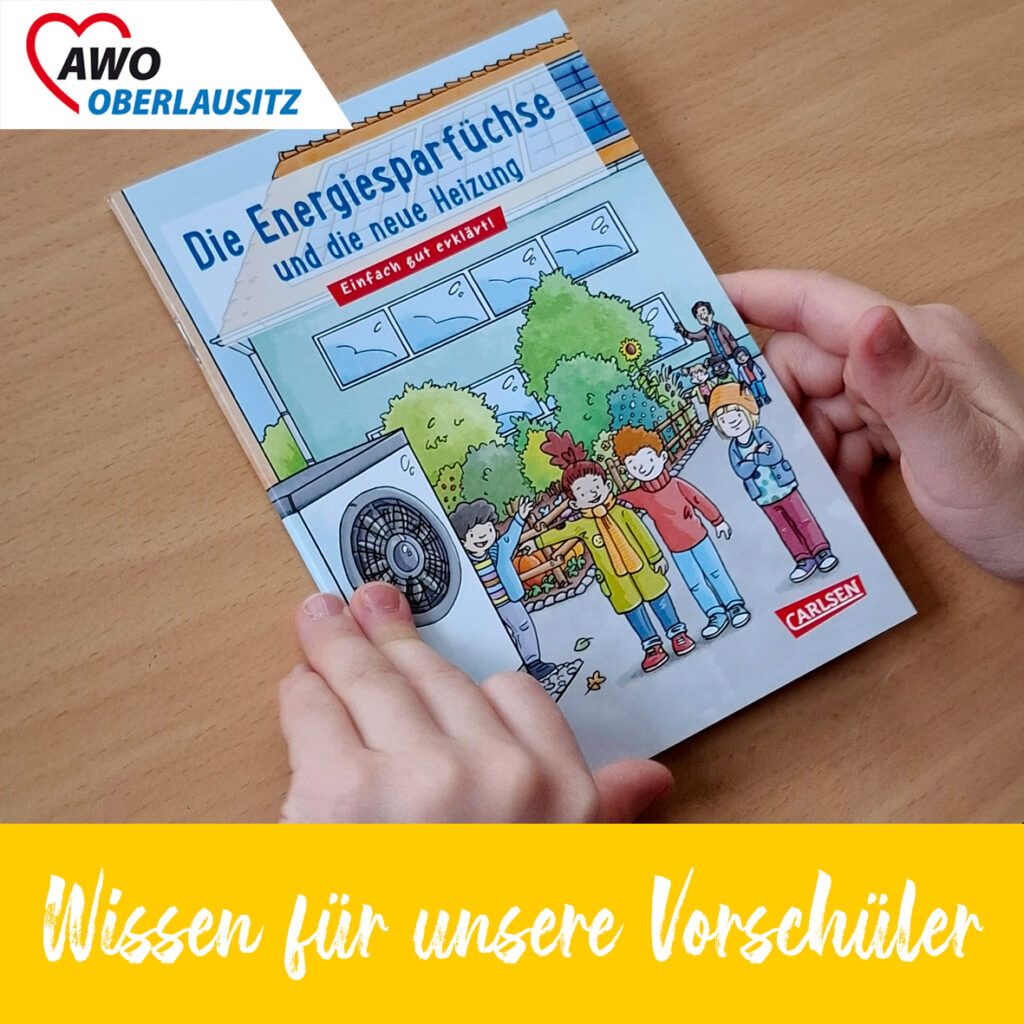 Kinderhände halten eine Pixibuch mit dem Titel "Die Energiesparfüchse und die neue Heizung".