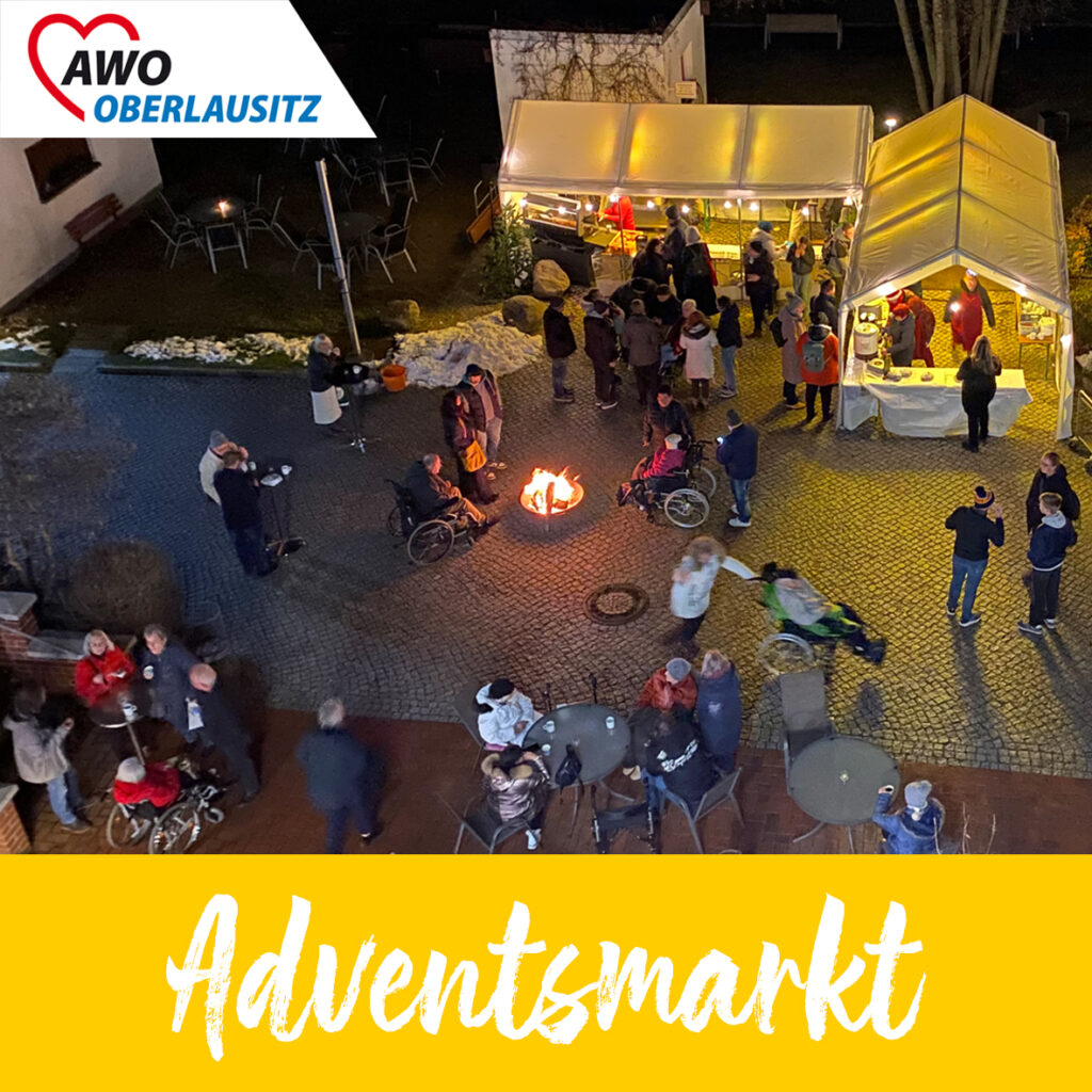 Von oben fotografierte weihnachtlich beleuchtete Buden und Stände vor dem Zentralhospital. Besucher und Bewohner bummeln über da Gelände. Auch wärmende Feuerstellen sind zu sehen.