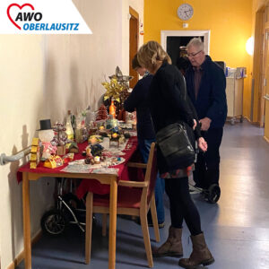 In den Gängen des Zentralhospitals befinden sich dekorierte Stände mit allerlei Selbstgebastelten Kunstwerken und Geschenken. Senioren und Besucher stehen davor und stöbern.