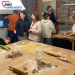 In der Küche des Altenheims tummeln sich Mitarbeiter, Kinderund Besucher und stechen gmeinsam Plätzchen aus und unterhalten sich.