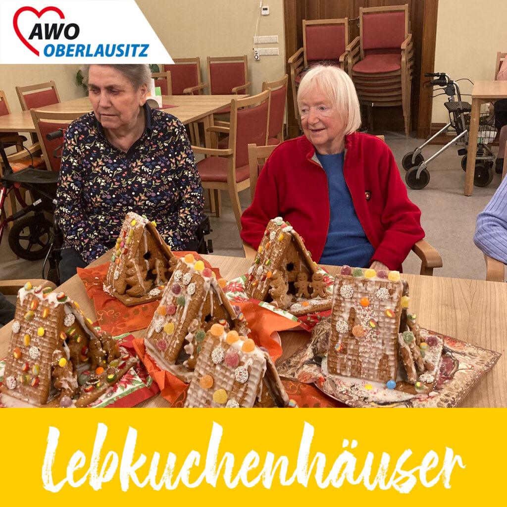 Im Vordergrund sechs bunte, lecker verzierte Lebkuchenhäuser, dahinter sitzen zwei ältere Bewohnerinnen - stolz lächelnd.