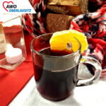 In einer Glastasse, dekorativ mit Zitronenscheibe am Glasrand, ist roter Glühwein.